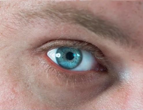 Close-up of a bright blue human eye with detailed iris and lashes