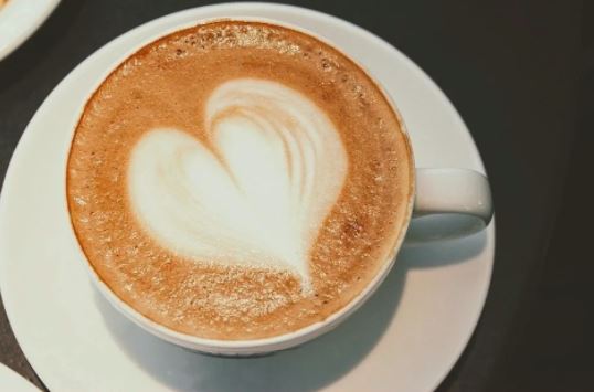 Close-up of a latte with a heart-shaped foam art on a white saucer
