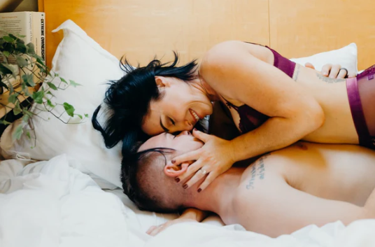 Intimate couple embracing in bed, symbolizing sex as emotion in motion