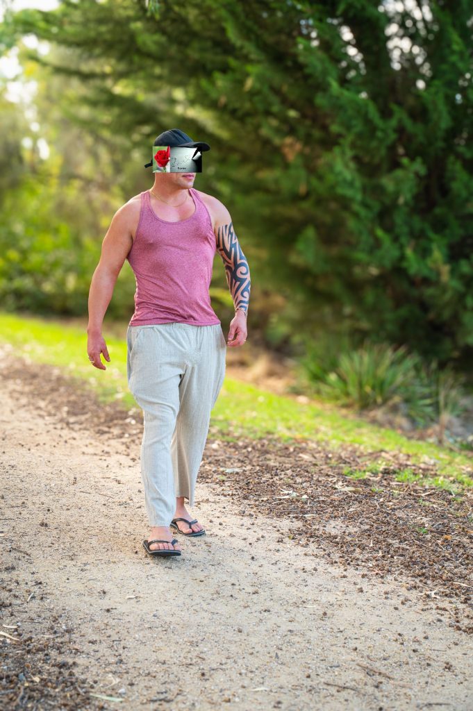 Man with tattoos walking on a dirt path in a forest, February 2025
