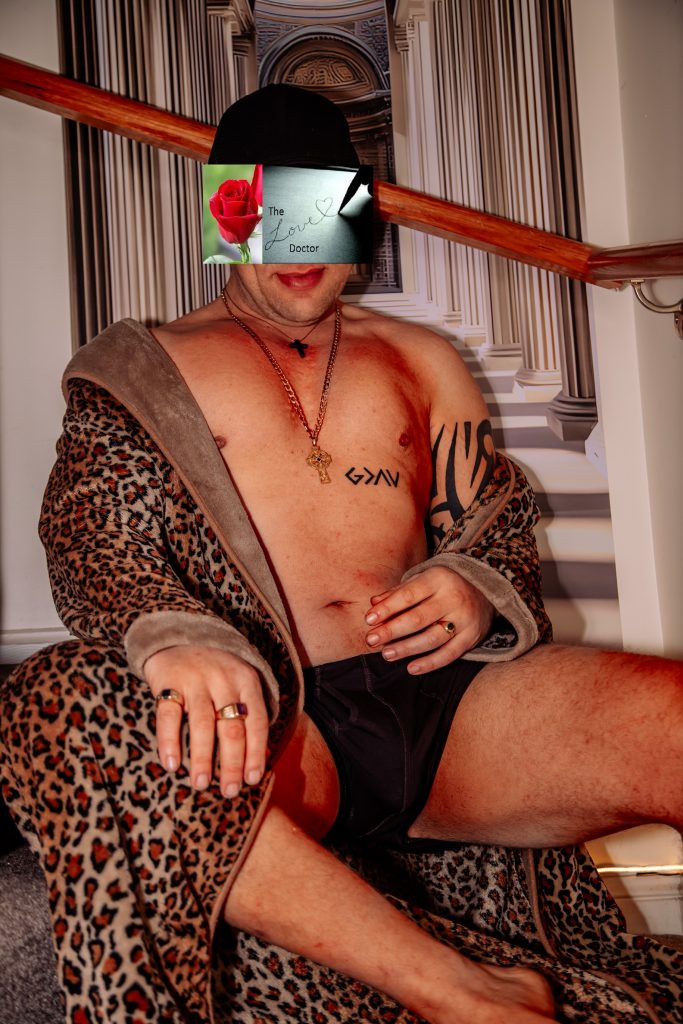 Man in leopard print robe and underwear, face obscured by a card with 