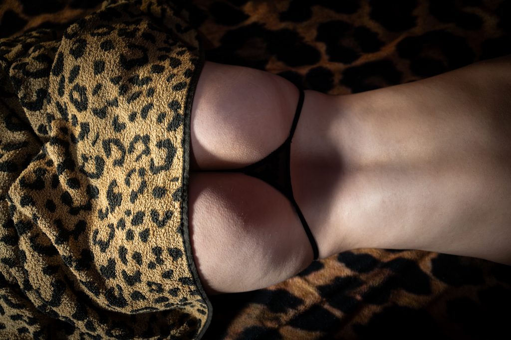 Close-up of a person's lower back and buttocks in a thong, covered by a leopard-print towel.