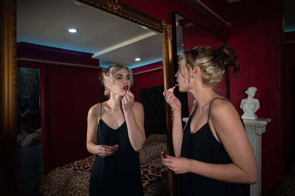 Woman applies lipstick in a ornate mirror, July 2026 gallery