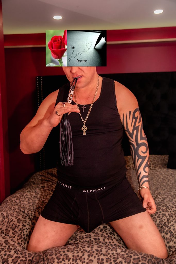 Man in black tank top and boxers holding a whip, with a rose and 